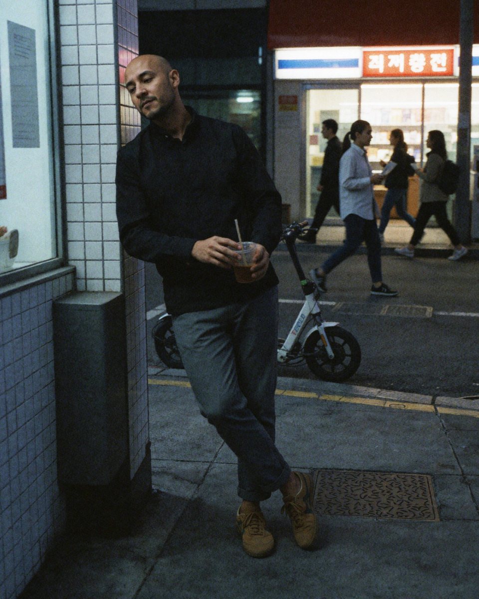 Sebastián Hortúa leaning on a tiled wall at night with a drink in his hand